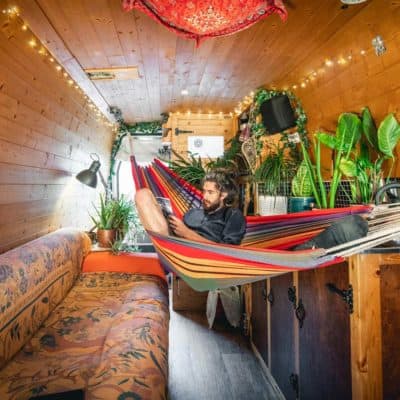 inside van conversion – mike sat in hammock reading a book