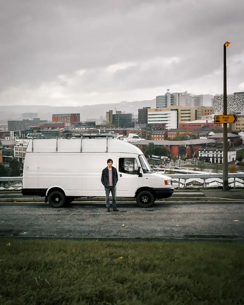 The van parked on a grey street in Sheffield the week before setting off, overcast sky, terraced houses behind.