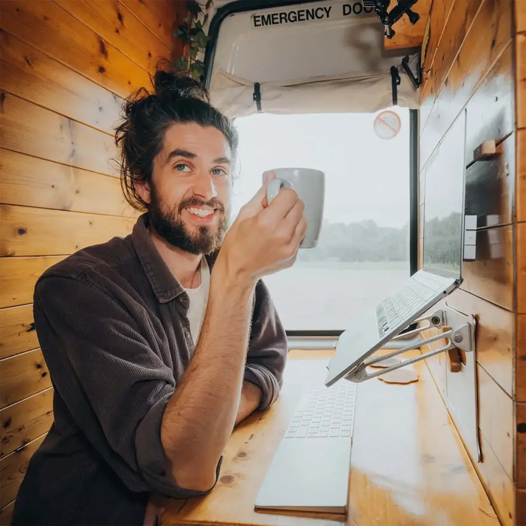 The van's builder leaning on the open rear doors, mug in hand, grinning.